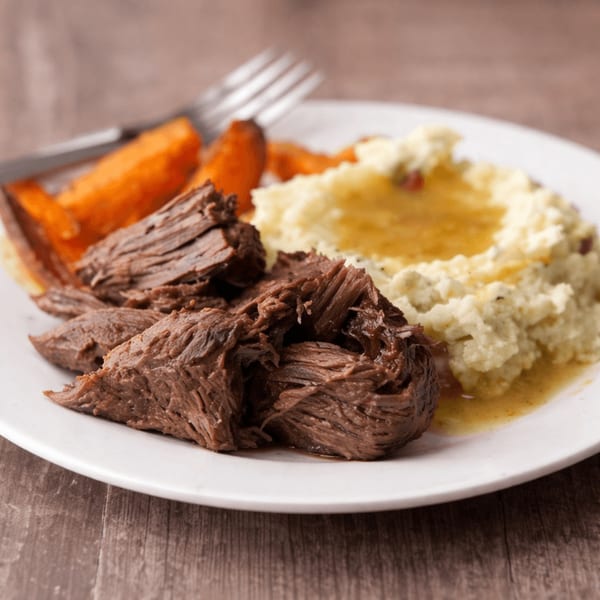 Dan's Soul Food and Cafe's pot roast with mashed potatoes and roasted carrots on a white plate.